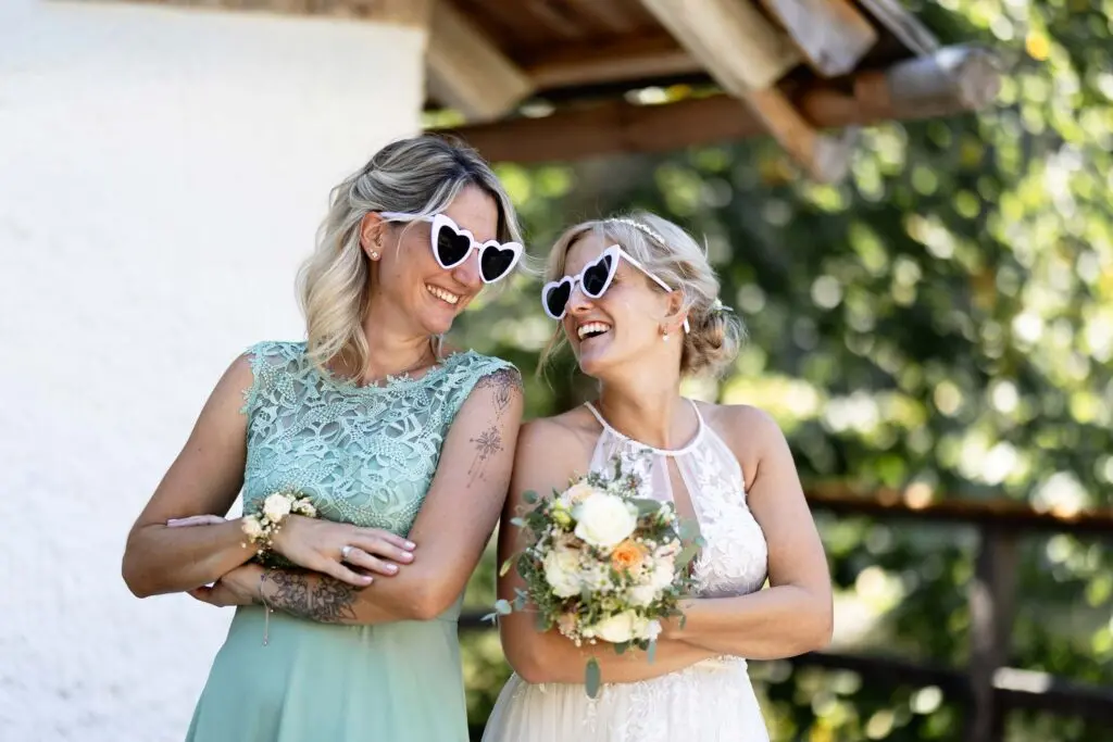 Braut im weißen Hochzeitskleid mit ihrer Trauzeugin bei einer Hochzeit am Haidensee