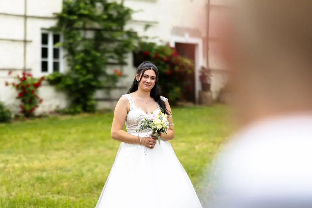 Braut im weißen Hochzeitskleid auf einer Wiese vor einem alten Gebäude im Drautal